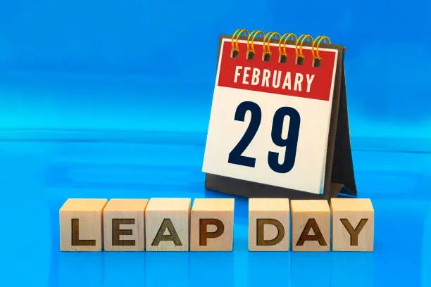 A calendar page on February 29 with wooden blocks with the text leap day on a blue background. Concept: Leap Year
