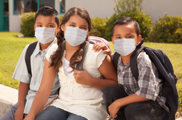 istock Young Hispanic Students on School Campus Wearing Medical Face Masks 1305207365