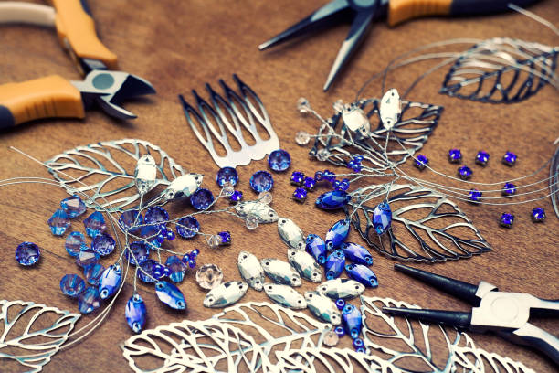 istock The process of creating jewelry with wire, rhinestones and crystals. Working tools on the table. Handmade jewelry. A bridal comb in the manufacturing process. 1305214531