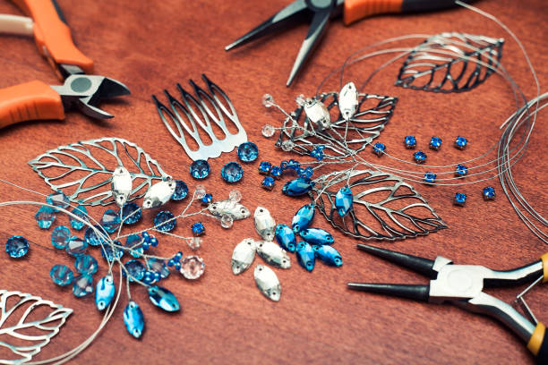 istock The process of creating jewelry with wire, rhinestones and crystals. Working tools on the table. Handmade jewelry. A bridal comb in the manufacturing process. 1305214629