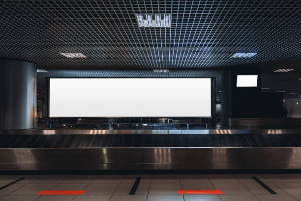 Mock-up of a billboard in airport A baggage claim area in a hall of a contemporary airport arrival zone with luggage conveyor belt and a mock-up of a long white empty advertising or information billboard and tv plasma screen arrival departure board photos stock pictures, royalty-free photos & images