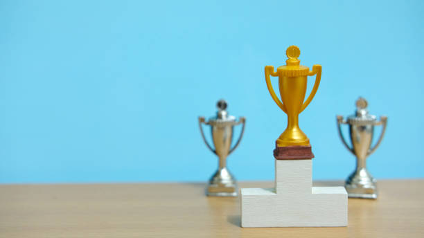 istock Golden trophy standing on white podium with two silver trophy at back 1305216793