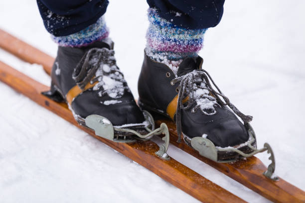 le skieur dans de vieilles bottes en cuir monte des skis en bois. concept de sports d’hiver - ski old wood pair photos et images de collection