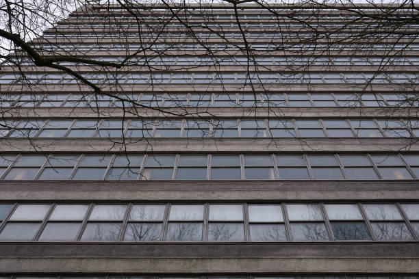 istock Low angle view of a post-war gray concrete office building with windows. 1305220285