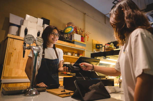 Making a contactless payment at a restaurant Photo of unrecognizable person making a contactless payment at a cafe with a credit card. asian cashier stock pictures, royalty-free photos & images