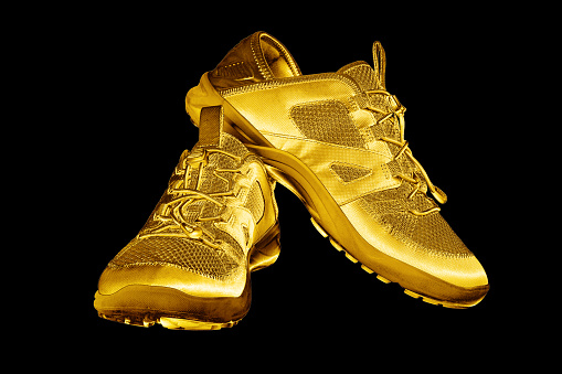 Golden sneakers black background isolated closeup, gold metal sport shoes, luxury running gumshoes, fashion yellow metallic fitness boots, athletic, football footwear, winner, victory, champion symbol