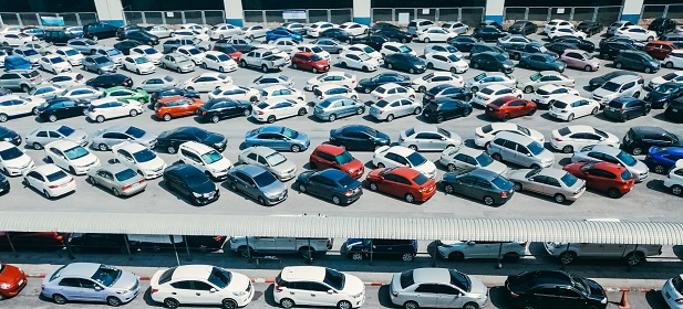 Aerial photograph of rows of cars parked in a large parking lot.