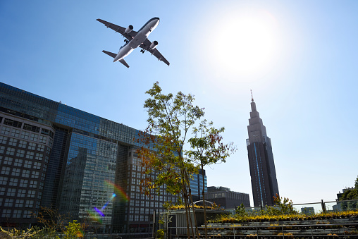 Low angle view of flying airplane over the skyscrapers against blue sky.