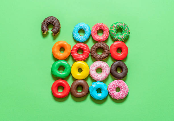 Chocolate donuts with multicolored icing, top view on a green background.
