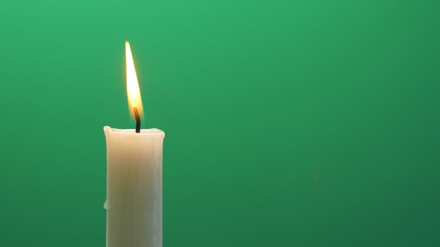 Closeup candle fire flame burning on chroma key green screen background 4K video