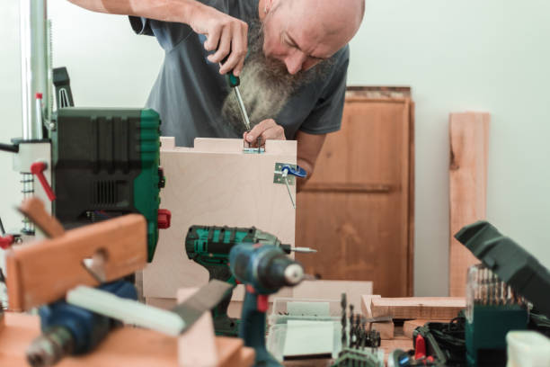 istock Man working in workshop, screwing wood screws 1305241260
