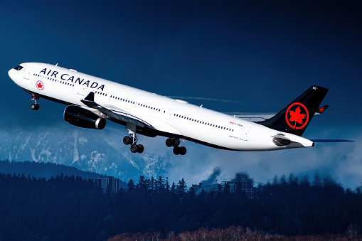 An Air Canada Airbus A330-300 in their new livery taking off past the mountains of Vancouver