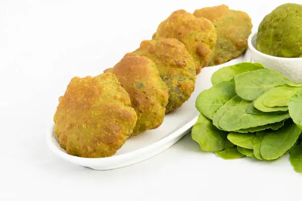 Photo of Unique And Real Taste Of India Puffed Palak Poori Or Spinach Masala Puri Stacked And Decorated In Tray With Fresh Green Leaves And Knead Dough. Isolated On White Background With Space For Custom Text