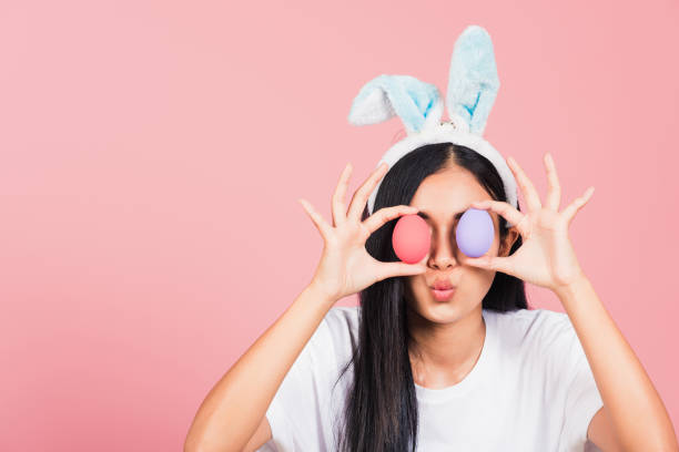 istock woman smiling wearing rabbit ears holding colorful Easter eggs front eyes 1305243204