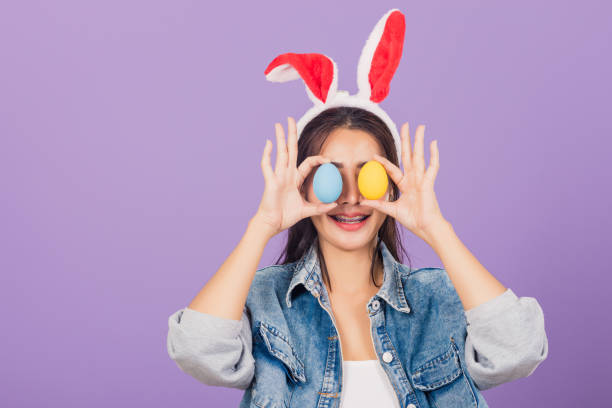 istock woman smiling wearing rabbit ears and denims holding colorful Easter eggs front eyes 1305243216