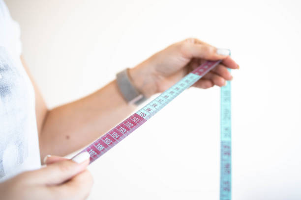 istock Woman's hand holding tailor measuring tape 1305248275