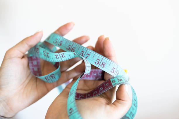 istock Woman's hand holding tailor measuring tape 1305248295
