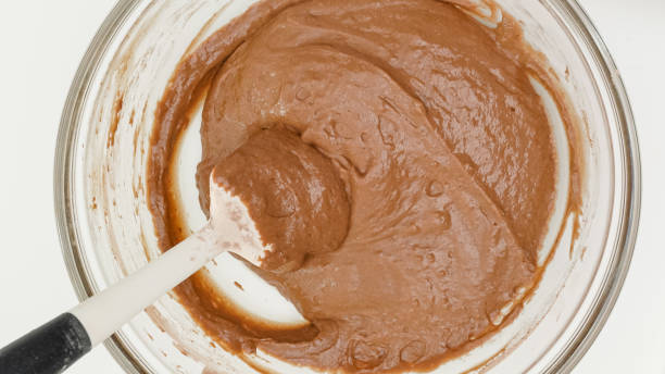 istock Chocolate cake recipe. Mixing cake batter in a glass bowl. Close up baking process, flat lay 1305250476