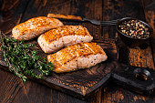 Fried Salmon Fillet Steaks on a wooden board with thyme. Dark wooden background. Top view