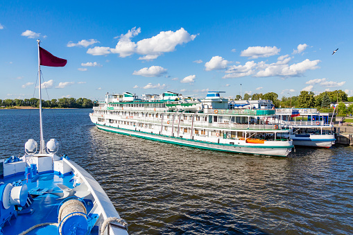 Two three-deck passenger ships at the berth in the city of Kazan. Volga River, Republic of Tatarstan, Russia. Shooting from the ship. A sunny summer day.