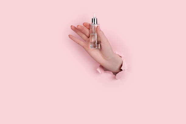 istock Female hand holding hyaluronic bottle from torn paper 1305253721