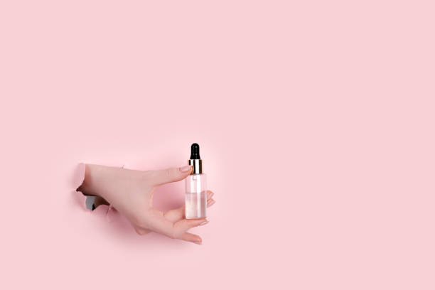 istock Female hand holding hyaluronic bottle from torn paper 1305253729