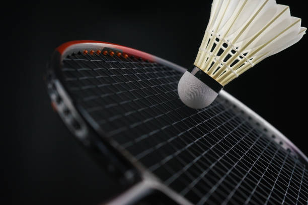 primo piano di un giocatore di badminton che colpisce una palla di badminton in una partita - racchetta da volano foto e immagini stock