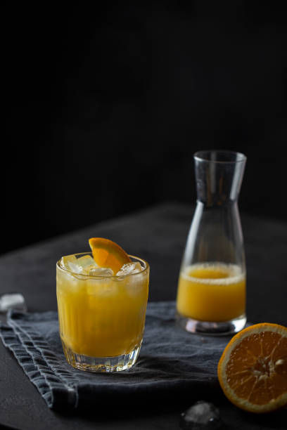 istock Orange juice glass with ice on dark background. Refreshment cold drink . 1305255142