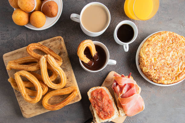 istock Different Spanish breakfast, tortilla, bruschetta with jamon (cured ham) and tomatoes, churros with chocolate,  Magdalena (Spanish cupcake) , crusty toast with butter and jam ,coffee and orange juice 1305255149