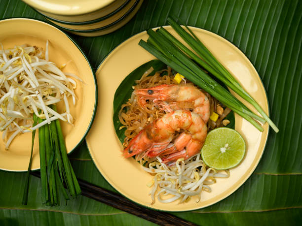 istock Pad Thai, stir fired Thai noodles with shrimps serving with lime, beansprouts and chives on Thai traditional plate on banana leaves 1305256708