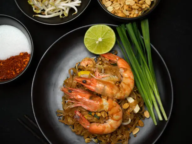 Top view of Thai food, stir fired Thai noodles with shrimps serving with lime, beansprouts and chives, Pad Thai