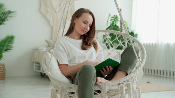 istock A woman reads a book while sitting on a swing at home 1305259381