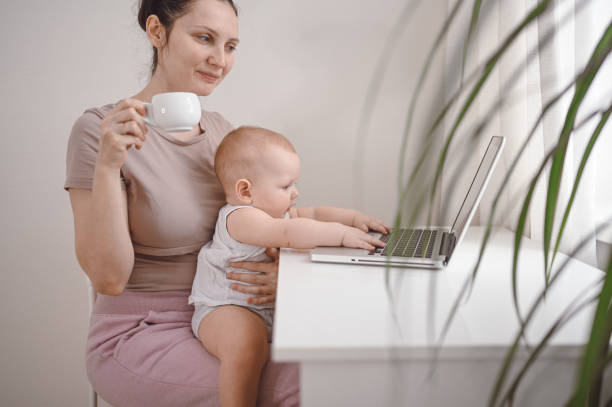 istock Young mother work studying from home with laptop computer during quarantine, little cute toddler baby on lap. Home office, parenthood. Remote work, distance education. Video conference virtual event. 1305261459