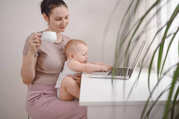 istock Young mother work studying from home with laptop computer during quarantine, little cute toddler baby on lap. Home office, parenthood. Remote work, distance education. Video conference virtual event. 1305262198
