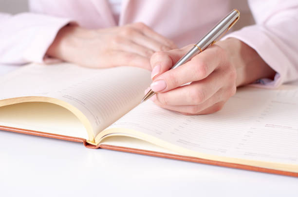 istock a woman writes down information with a pen in a diary 1305262596