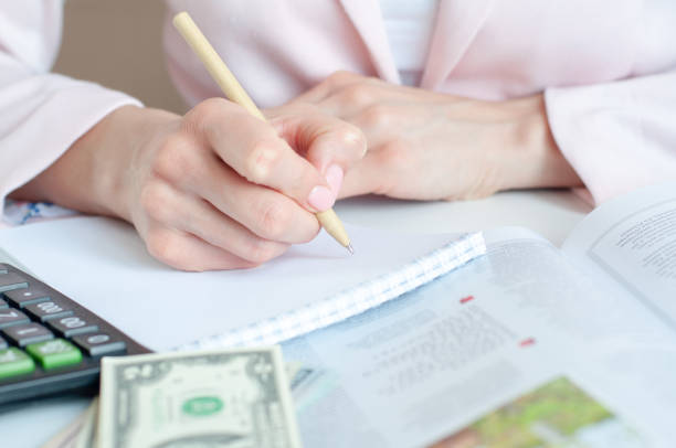 istock close up of woman hands with calculator counting and taking notes to notebook 1305262603