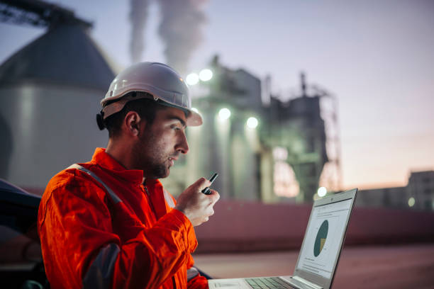 Engineer with laptop working in oil refinery stock photo