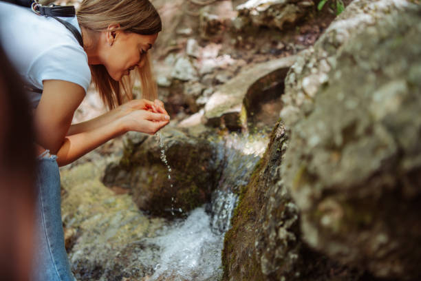 istock Young woman washing face in mountain river 1305263794