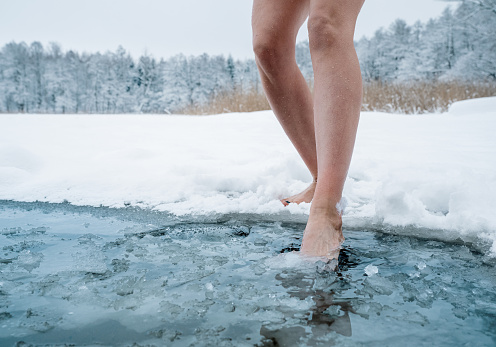 Close up of female legs getting into ice cold water