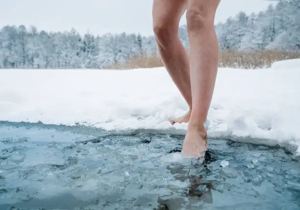 Photo of Close up of female legs getting into ice cold water