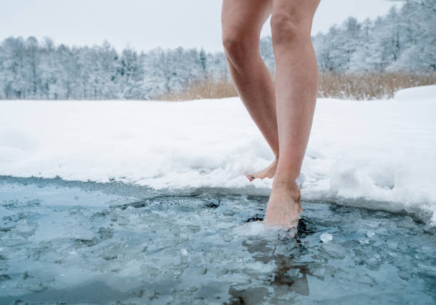 feche acima das pernas femininas entrando na água gelada - winter lake snow water - fotografias e filmes do acervo