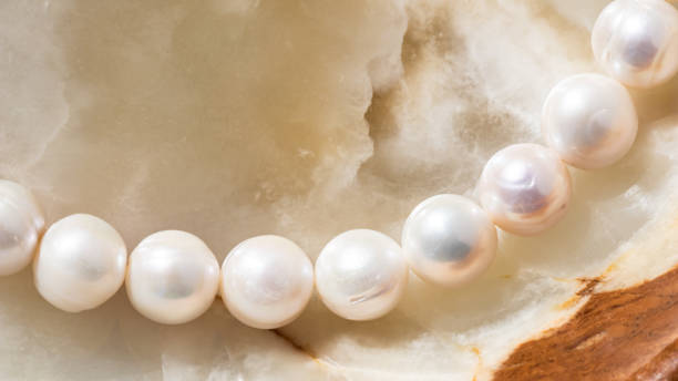 istock Nature white string of pearls on marble background in soft focus, with highlights 1305264120
