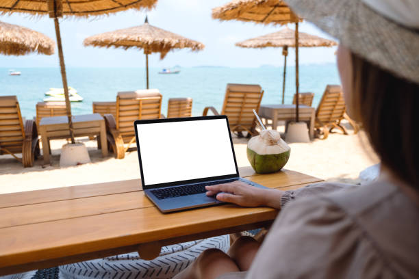 istock a woman using and touching on laptop touchpad with blank desktop screen while sitting on the beach 1305265173