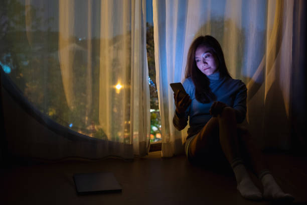 istock A sad young woman using mobile phone with bright light screen in the late night at home 1305265175
