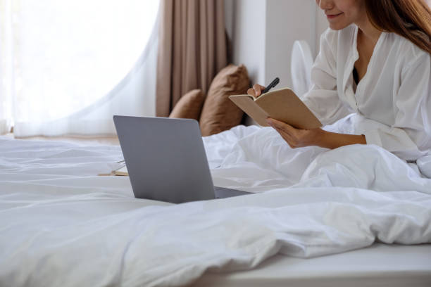 istock a woman using and working on laptop computer while sitting on the bed at home 1305265259