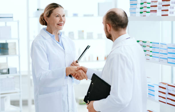 istock female pharmacist greets a colleague with a handshake 1305265395