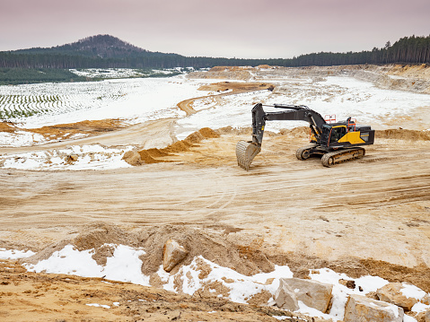 Loading excavators rest during the weekend. A large mine on white glass sand with several floors.