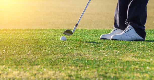 Zoomed in shot of a ball that is placed on a golf course and a golfer that is about to swing. Zoomed in shot of a ball that is placed on a golf course and a golfer that is about to swing. High quality photo golfer swinging club stock pictures, royalty-free photos & images