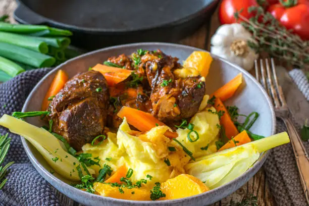 Ossobuco with mashed potatoes and oranges served with steamed carrots and fennel vegetable on a plate. Ready to eat