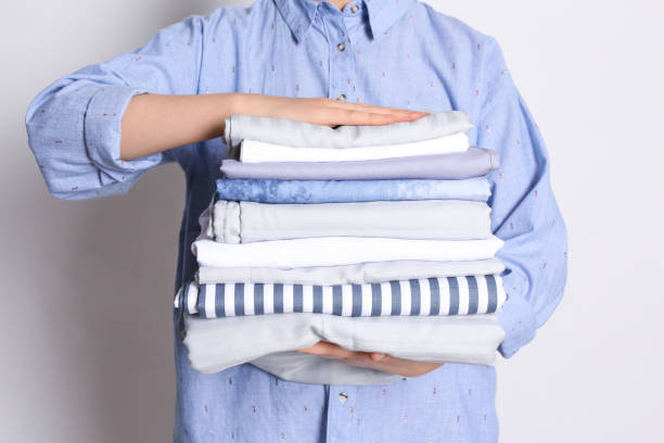 istock Woman holding stack of clean bed linens on white background, closeup 1305272367
